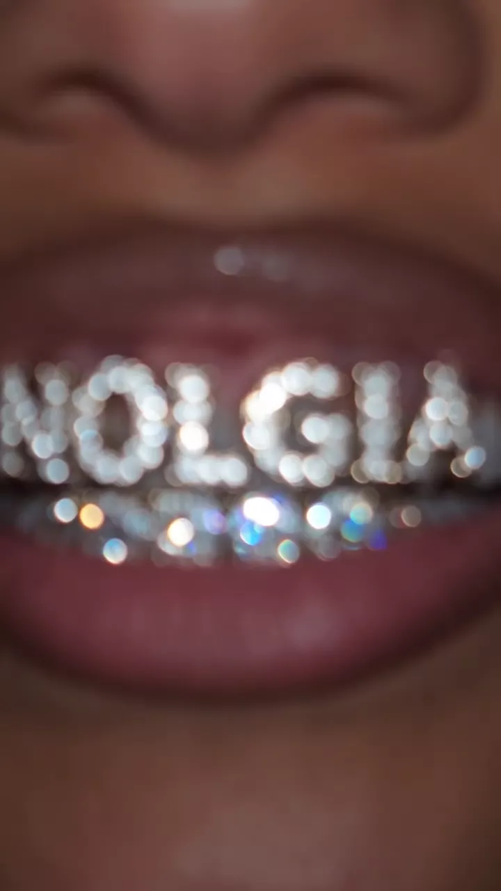 A draft: the word NOLGIA in large diamond letters spreads across her lips and past her teeth