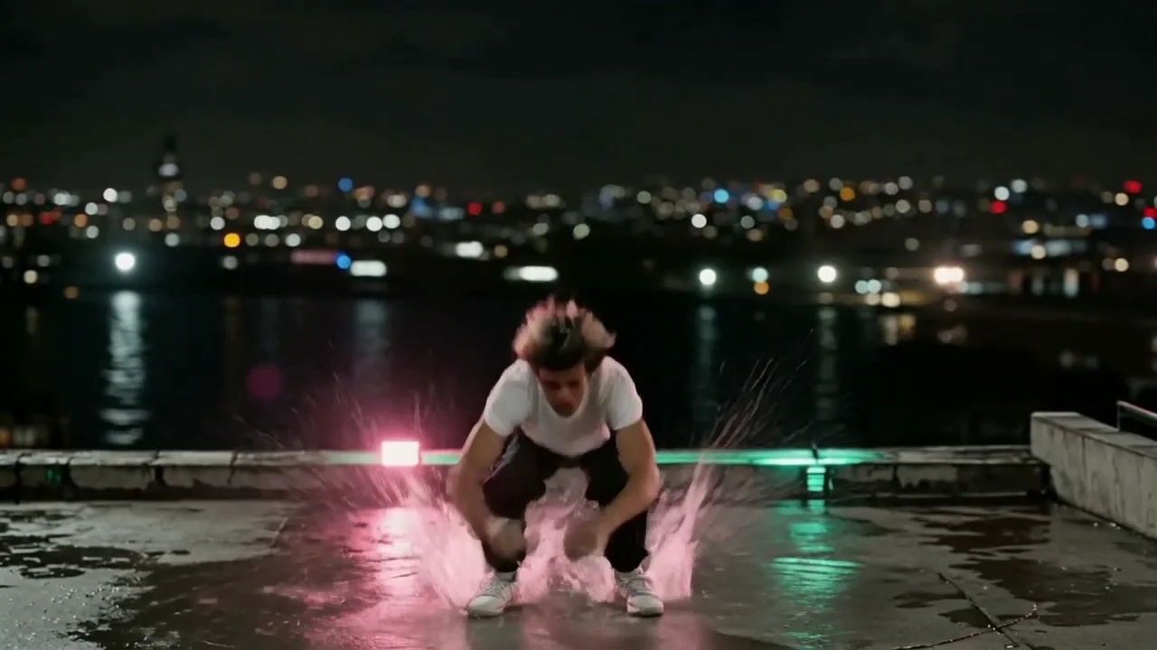 The rooftop backflip on Kling v3, third roll: a crouch, one tucked rotation and both feet landing together in a deep squat with a splash