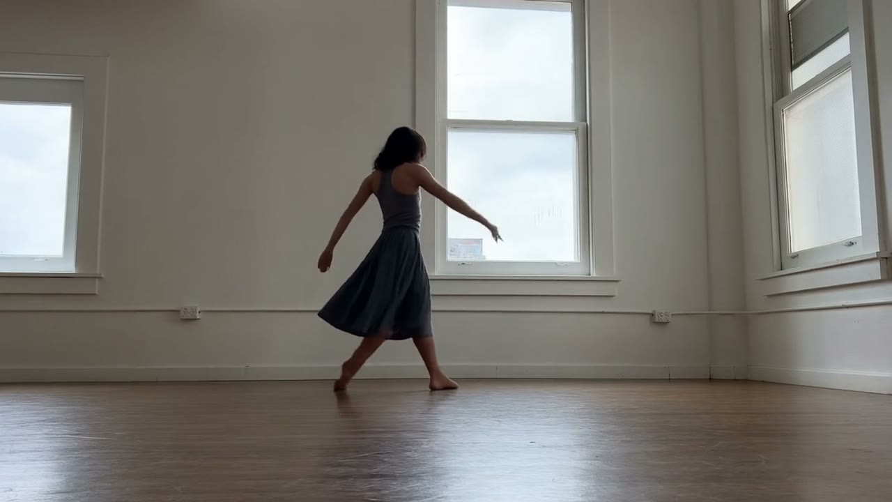Ejemplo creado con Hailuo 2.3: A dancer drops into a low spin on a scuffed studio floor, skirt flaring and settling with believable weight, hair following a beat late. Hard side…