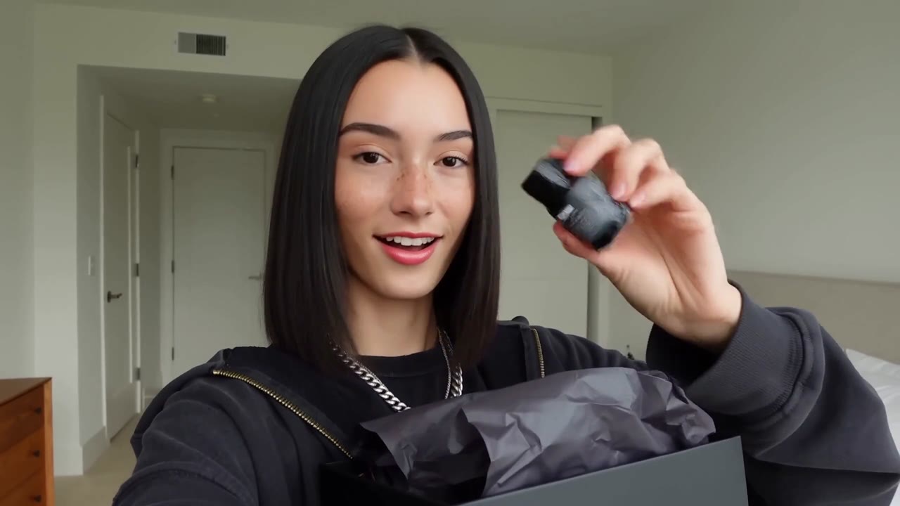 Selfie style UGC unboxing: a Gen Z creator in edgy designer streetwear opens a matte black box and reveals the product to camera with a genuine reaction