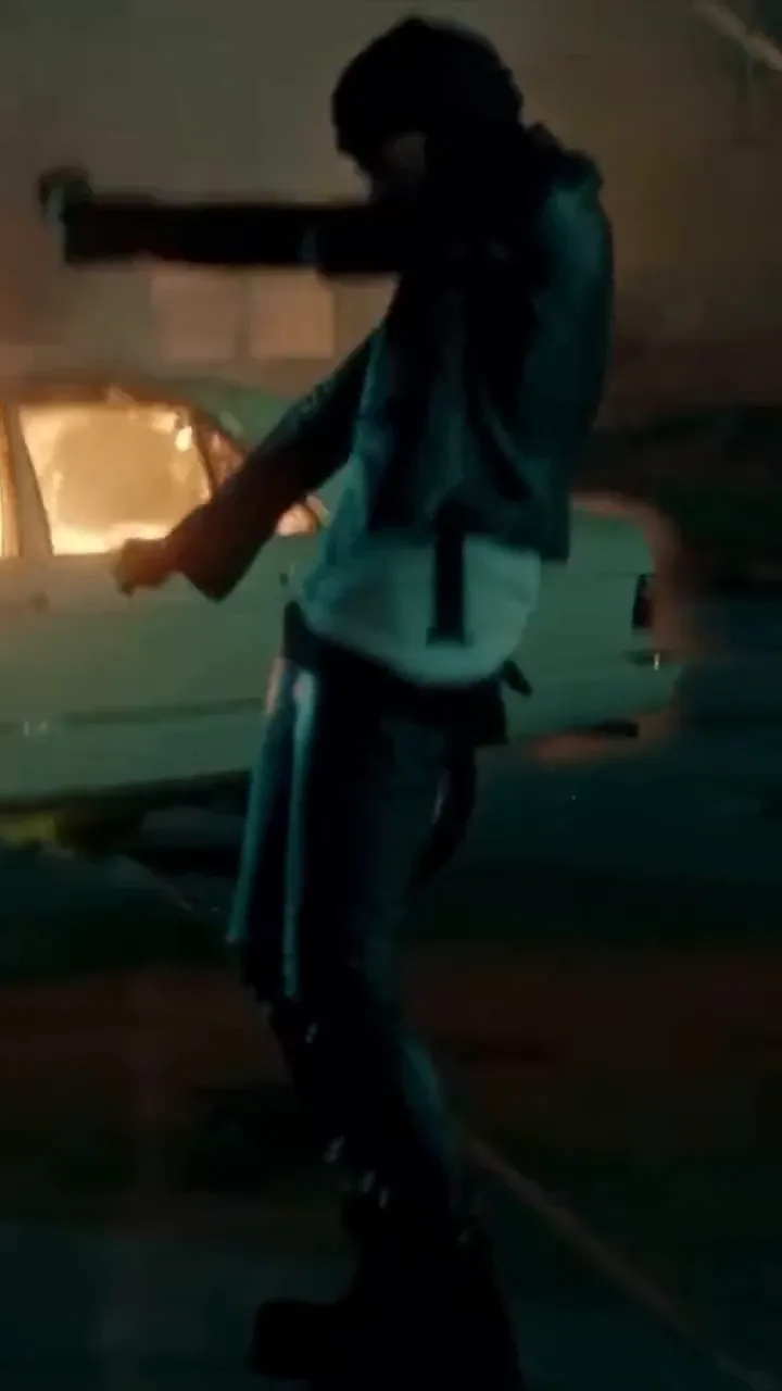 The source clip: a masked performer in a black leather jacket dancing at night in front of a burning car, then a performer in a skeleton print hoodie in a parking garage